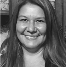 A smiling woman with long hair in a casual setting.